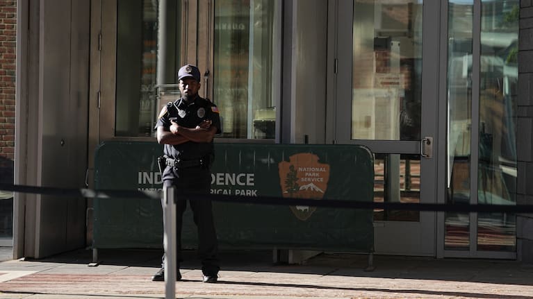 A guard stands at the entrance to The Liberty Bell center that is closed due to a government shutdown in Philadelphia.