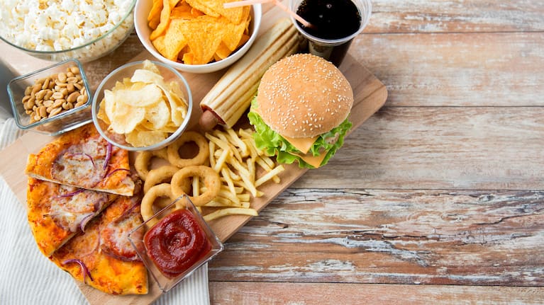 fast food, junk-food and unhealthy eating concept - close up of fast food snacks and coca cola drink on wooden table