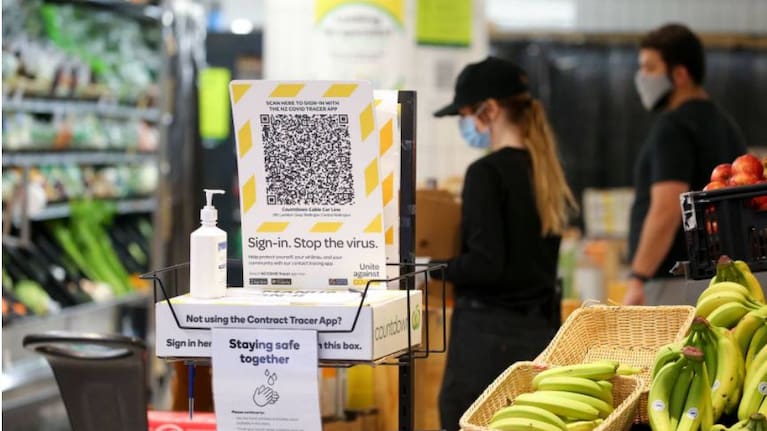 A NZ Covid Tracer App QR code and hand sanitiser sit at the entrance to a Countdown supermarket.