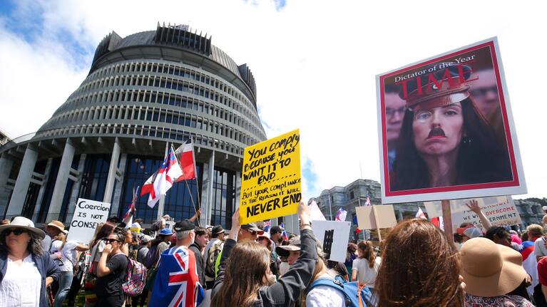 A protestor holds a sign displaying the image of Prime Minister Jacinda Ardern