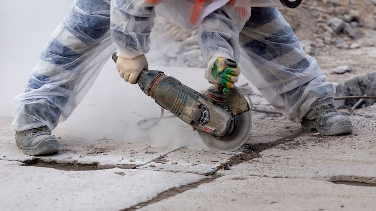 A worker using a saw to cut concrete (file).