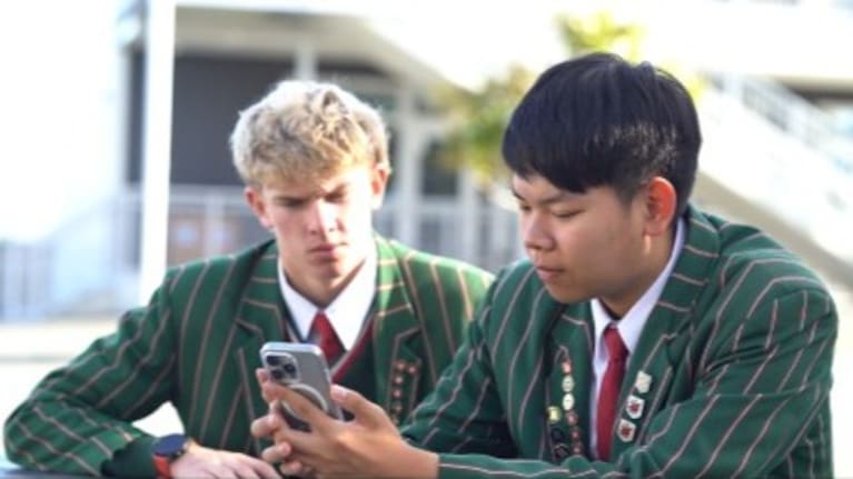 Alex Liang demonstrates his app to a fellow student.