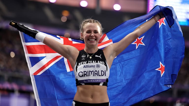 Anna Grimaldi  celebrates with a New Zealand flag after winning bronze during the Women's 100m T47 Final.
