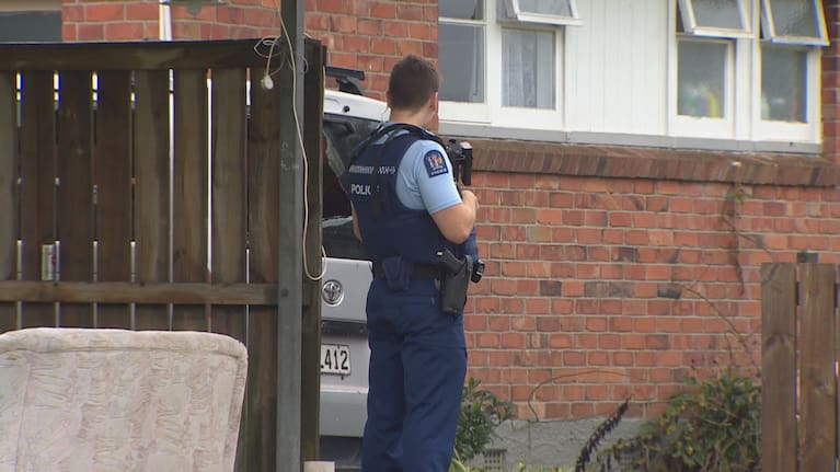 Armed policeman guards house in Glen Innes Auckland after it was shot at.