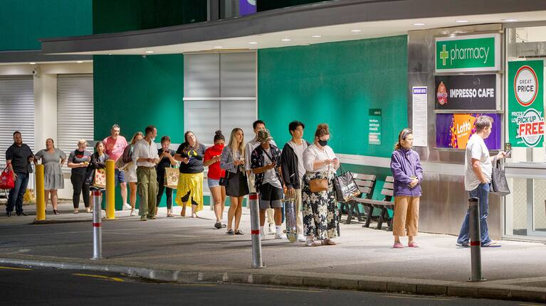 Shoppers queue outside a supermarket.