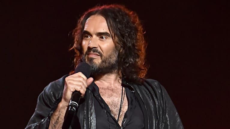 A woman has accused comedian Russell Brand of pinning her to the sofa in his dressing room.