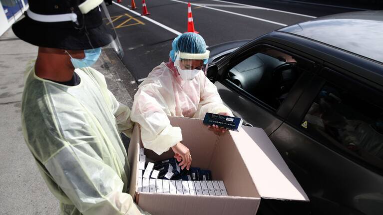 Health workers hand out rapid antigen tests in Henderson, Auckland.