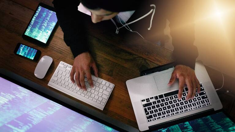 High angle shot of a hacker cracking a computer code in the dark