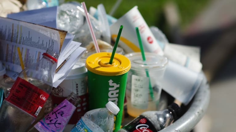 Miami - December 6, 2017: Consumer trash from fast-food chains, drinks brands, and plastic water bottles overflows from a public garbage can on the street outside Art Basel Miami Beach art fair.