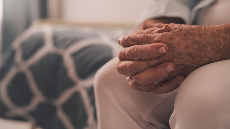 Cropped shot of a senior woman sitting with her hands clasped in a retirement home