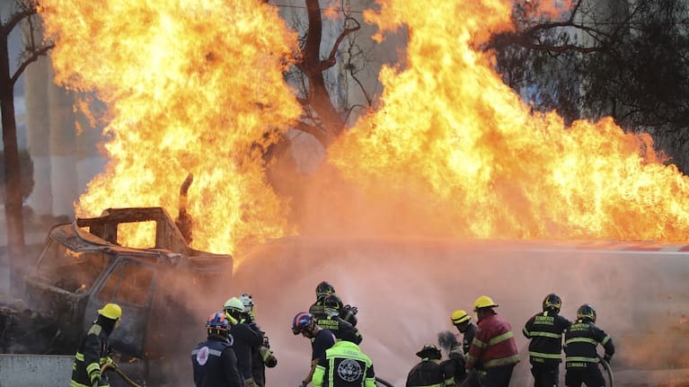 Firefighters spray hoses at a gas tanker that exploded under a highway overpass in Mexico City.