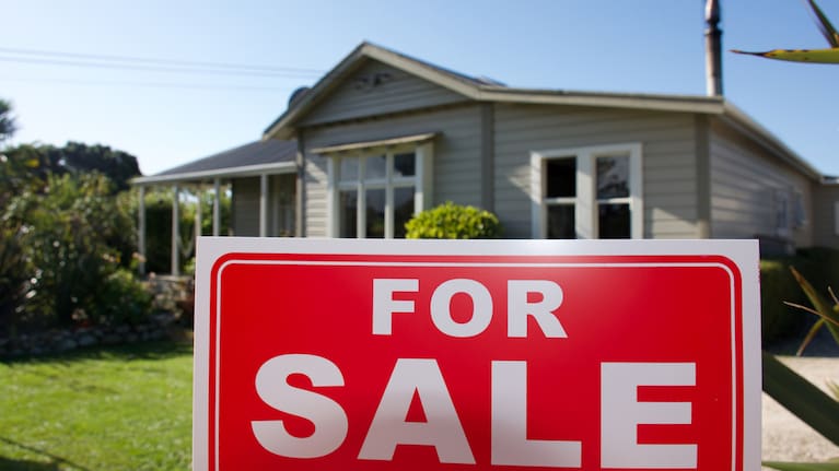 A for sale sing outside a house.