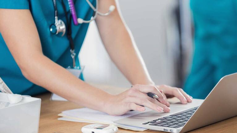 Healthcare worker using laptop - stock image