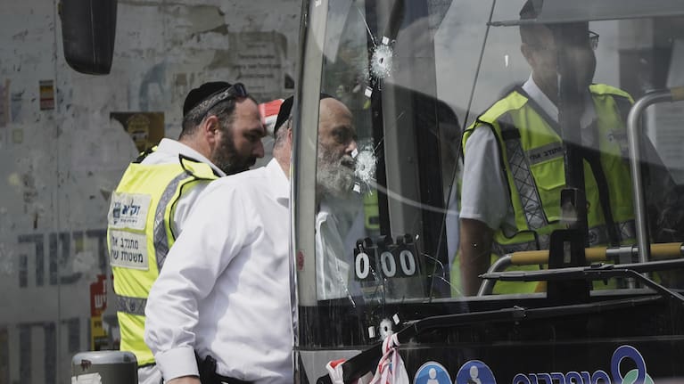 Israeli police and rescue teams inspect the scene of a shooting attack carried out by two Palestinian gunmen, in which several people were killed and others injured at a bus stop in Jerusalem