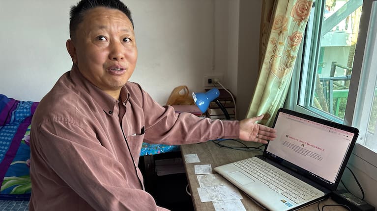 Lu Taizhi, a Chinese Christian who is waiting to be resettled in the United States, points to the webpage of the International Rescue Committee, which is under maintenance