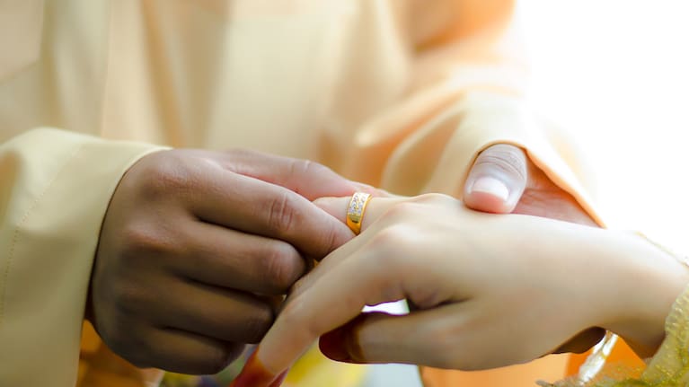 Malay wedding ceremony, Malaysia. Groom putting a diamond ring to his bride’s finger