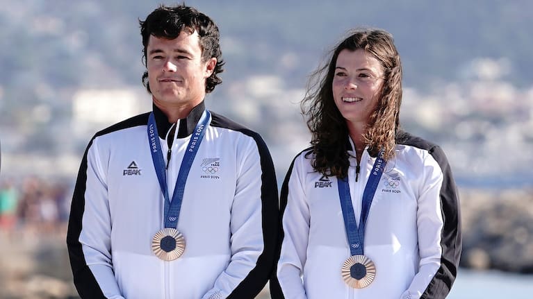 Micah Wilkinson and Erica Dawson of New Zealand celebrate winning the bronze medal on the podium of the Mixed Multihull Sailing, at the 2024 Olympic Games .