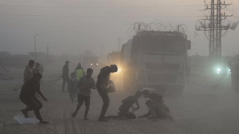 Palestinians rush toward trucks carrying aid from the World Food Programme (WFP) as they drive through Deir al-Balah in central Gaza.