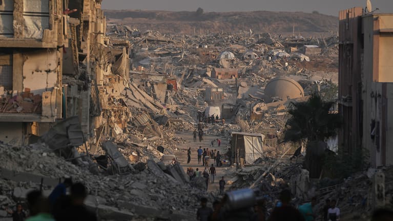 Palestinians walk trough the destruction caused by the Israeli air and ground offensive in Gaza City