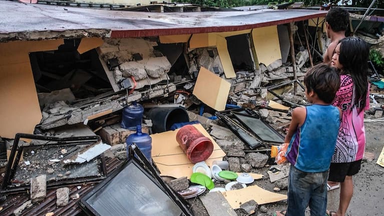 People look at a collapsed building in Bogo City, Cebu province, Philippines.
