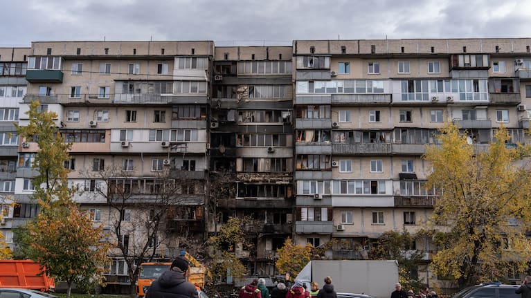 People look at a damaged apartment building following a Russian attack.