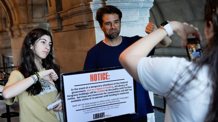 People take photos with a sign announcing that the Library of Congress is closed, on the first day of a partial government shutdown