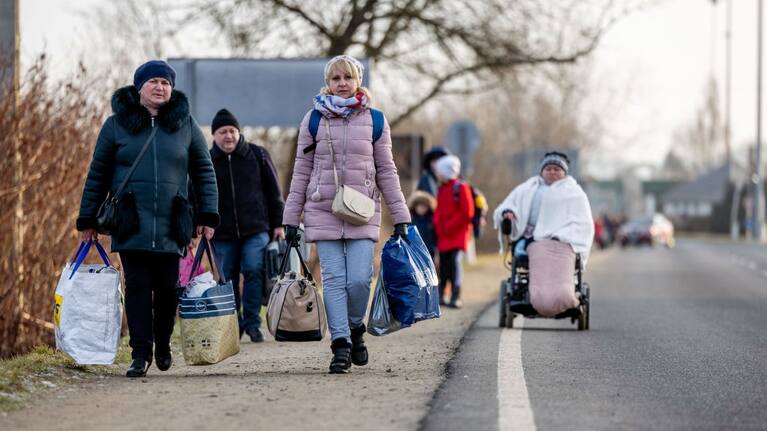 People walk with their belongings at the Astely-Beregsurany border crossing as they flee Ukraine on February 25, 2022 in Beregsurany, Hungary.