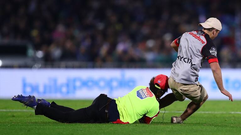 A pitch invader is tackled by security at McLean Park during last night's Warriors defeat.