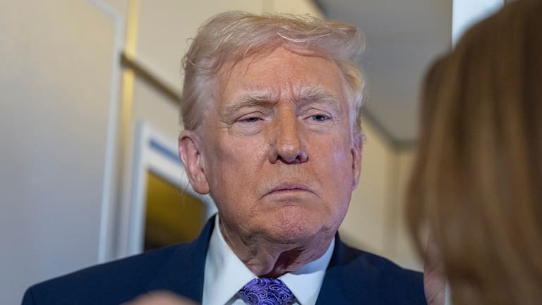 President Donald Trump speaks with reporters while in flight on Air Force One from his Mar-a-Lago estate in Palm Beach, Florida