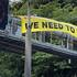 Restore Passenger Rail protesters hang a banner from a SH1 gantry.
