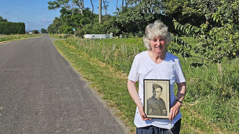 Robyn Askey with a photograph of her father, returned serviceman Laurie McLaren, who planted the phoenix palm in the background in 1950 when he was settled on the Putiki Road farm. (Source: Diane McCarthy)