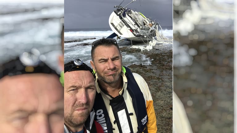 Roger Young and Geoff Marsland take a photo with their stranded yacht.