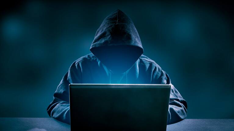 Shadowy figure using a laptop.