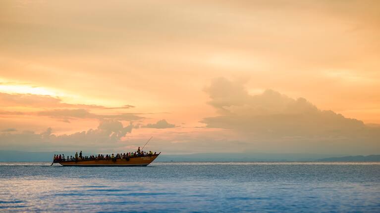 Lake Tanganyika, Tanzania - December 28, 2009: Sunset behind a crowded boat is transporting refugees on Lake Tanganyika from the DR Congo into Tanzania.