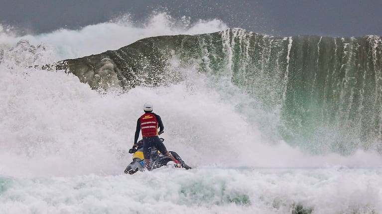 A surf lifeguard on a jetski faces a wall of water at Piha. Photo: Rob Ferguson