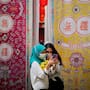 Two Malay girls check a mobile phone at a fabric installation decoration in downtown Kuala Lumpur, Malaysia, in 2021.