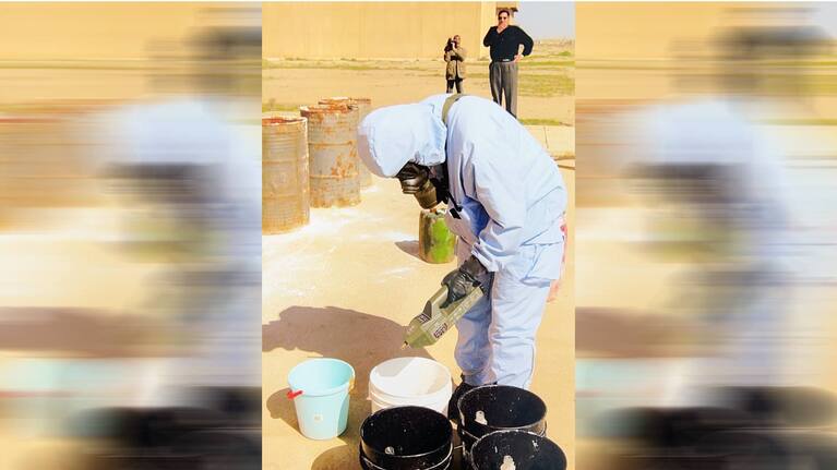 UN personnel in protective gear inspects buckets in Iraq.