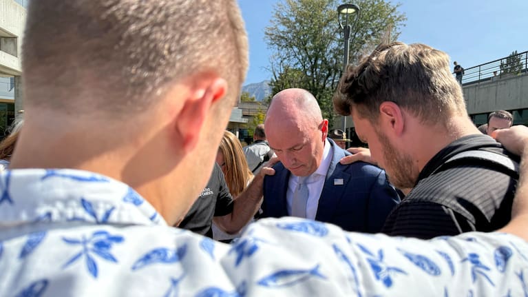 Utah Governor Spencer Cox, centre, prays with students at Utah Valley University.