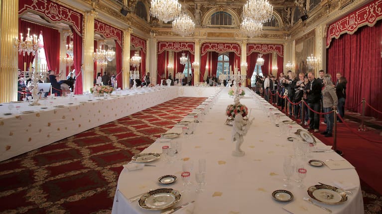 Visitors view a table dressed with plates and glasses for official dinners at the Elysee Palace in Paris, Saturday
