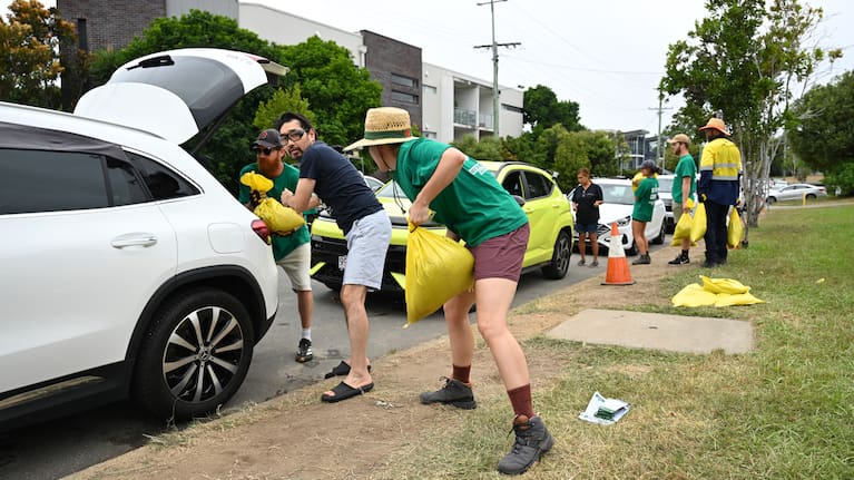Volunteers help load sandbags into residents' cars at a sandbag depot in Brisbane yesterday.